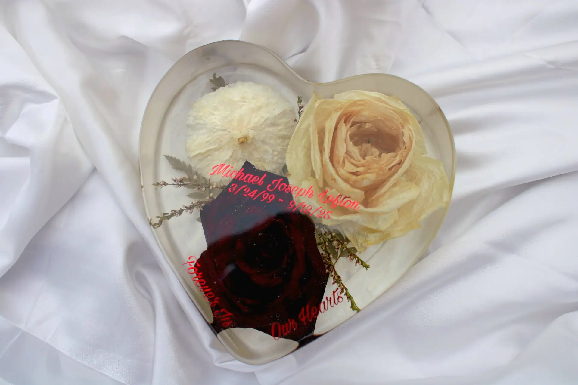 Heart-shaped resin memorial keepsake with preserved flowers.